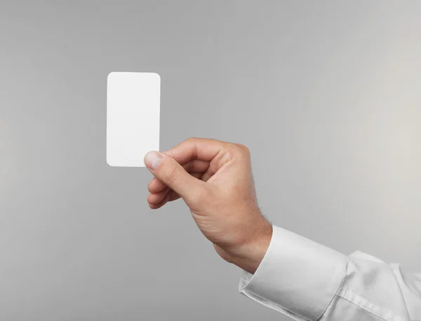 Man's hand holding white card on light background — Stock Photo, Image