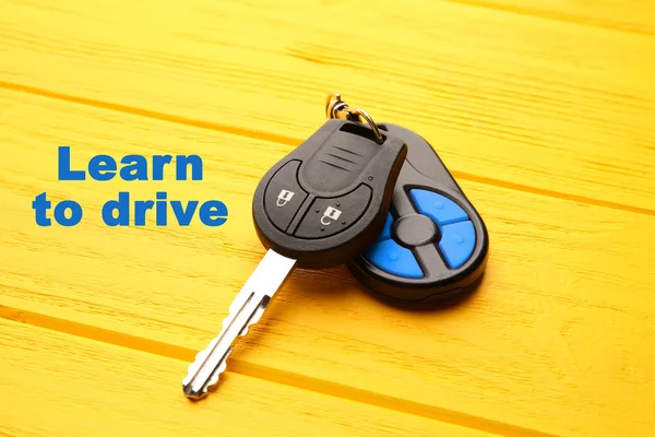 Learn to drive. Car key on yellow table — Stock Photo, Image