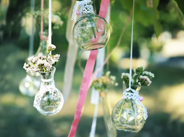 Mini vases with bouquets of flowers hanging on ribbons outdoor — Φωτογραφία Αρχείου
