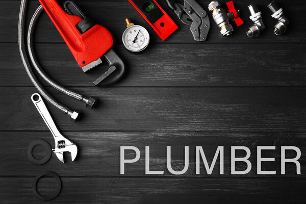 Plumbing concept. Plumber tools on a gray wooden background