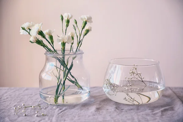 Jarrones de vidrio con flores en la mesa — Foto de Stock
