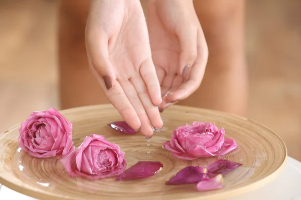 Mani femminili in spa ciotola di legno con fiori, primo piano — Foto Stock