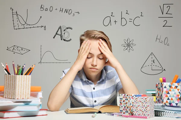 Tired Boy Studying Table Different Subjects Signs Gray Background Education — Stock Photo, Image