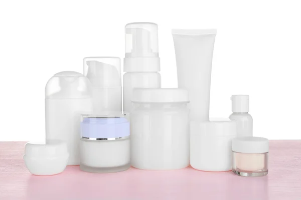 Frascos cosméticos diferentes na mesa no fundo branco — Fotografia de Stock
