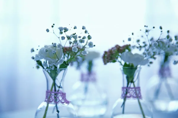 Mini skleněné vázy s květinami na stole — Stock fotografie