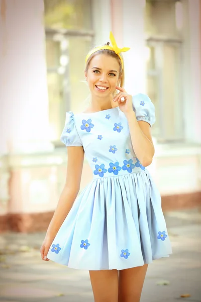 若い女性の美しいフラワー プリントのドレスを着て 建物の背景がぼやけでポーズ — ストック写真