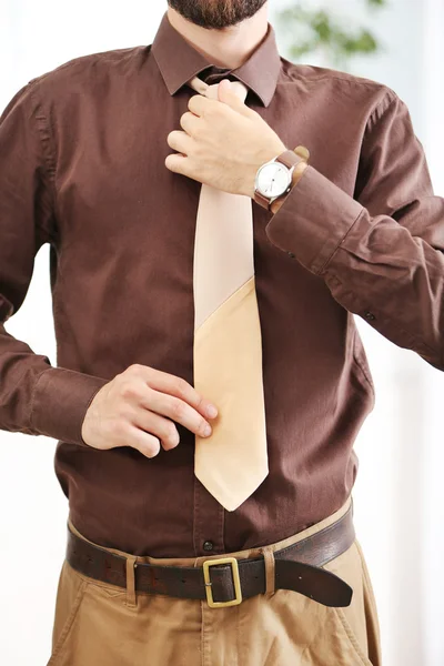 Man adjusting leather tie in office — Stock Photo, Image