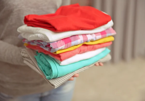 Woman holding pile of clothes — Stock Photo, Image