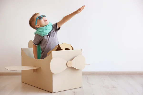 Liten pojke leker med kartong flygplan — Stockfoto