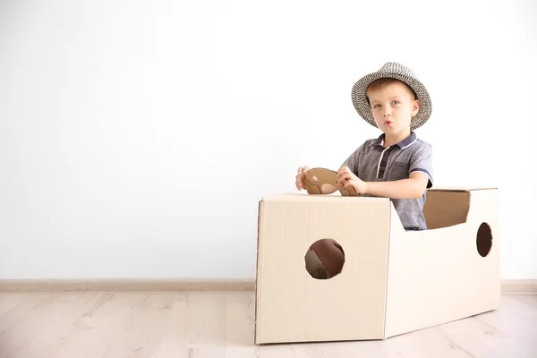 Маленький хлопчик грає з картонним кораблем — стокове фото