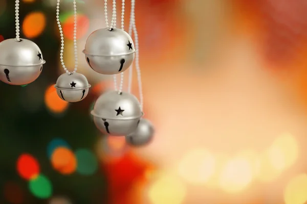 Glocken klingeln auf verschwommenem Weihnachtsbeleuchtungshintergrund, Nahaufnahme — Stockfoto