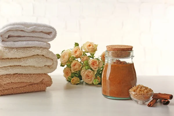 Spa concept. Natural facial mask with cinnamon, pile of towels and flowers on white table — Stock Photo, Image