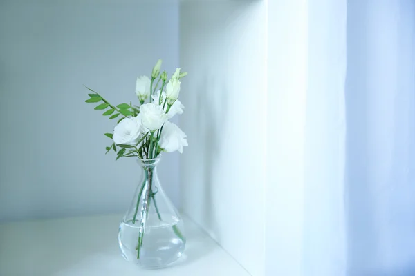 Lindas flores eustoma em vaso de vidro na prateleira branca — Fotografia de Stock