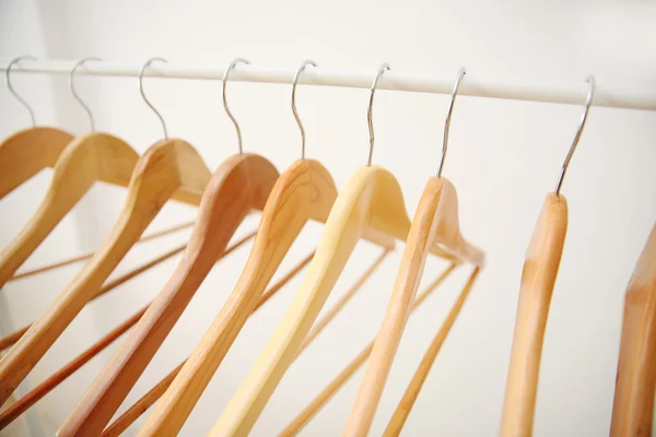 Wooden coat hangers on clothes rail and white background — Stock Photo, Image