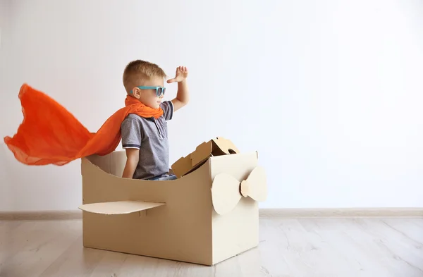 Маленький хлопчик грає з картонним літаком — стокове фото