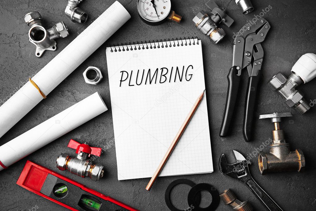 Plumbing concept. Notebook and plumber tools with blueprints on concrete structure background