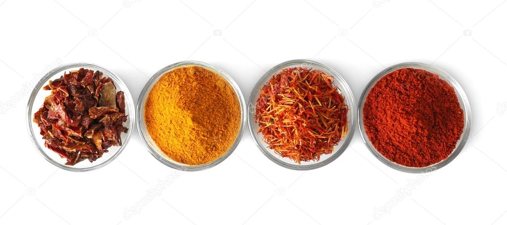 Glass bowls with various spices in a row on white background