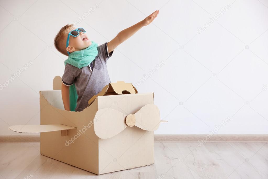 Little boy playing with cardboard airplane 