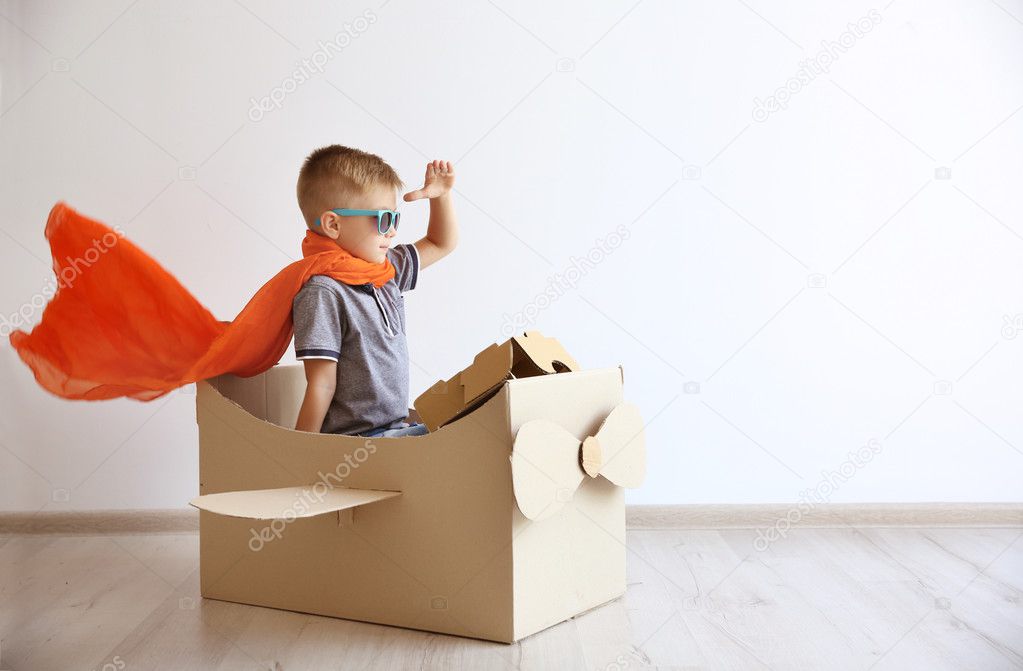 Little boy playing with cardboard airplane 