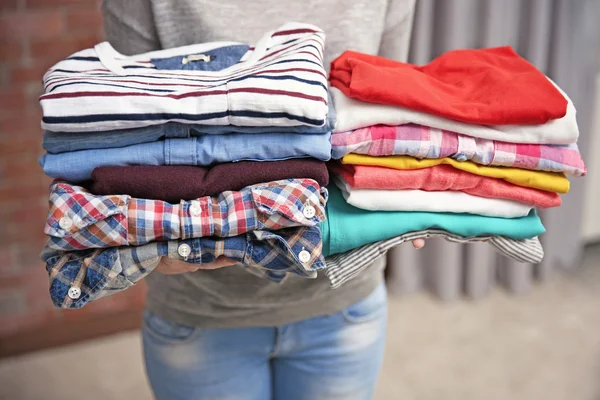 Woman holding piles of clothes, closeup — Stock Photo, Image