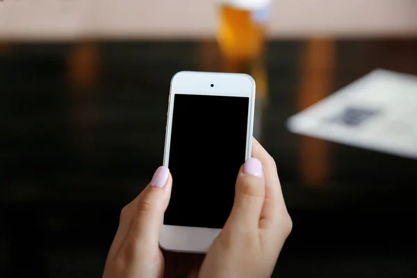 Manos femeninas sosteniendo el teléfono inteligente sobre fondo borroso —  Fotos de Stock