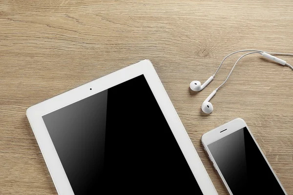Tablet, smartphone e fones de ouvido em uma mesa, close-up — Fotografia de Stock