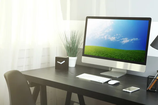 Pohodlné pracoviště s moderním počítačem a zelené jarní pole na obrazovce — Stock fotografie