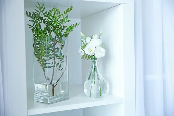 Piękne kwiaty w wazonach szkła na półce białe — Zdjęcie stockowe