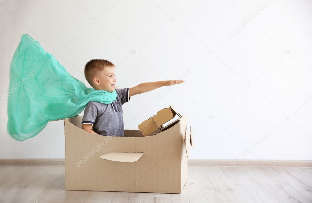 Little boy playing with cardboard airplane 