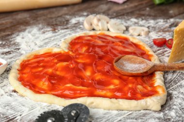 Pizza hamur masada domates sos ile kaplı kalp şeklinde