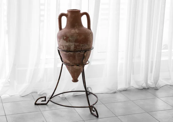 Ancient amphora on stand on curtain background — Stock Photo, Image