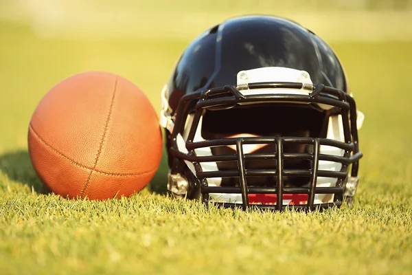 Capacete de rugby com bola no campo — Fotografia de Stock