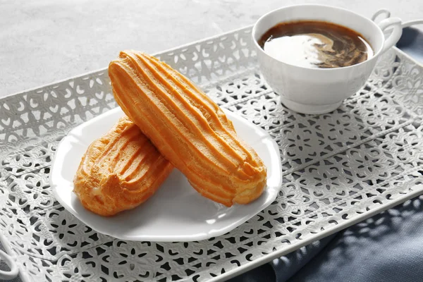 Deliciosos eclairs e xícara de café na mesa — Fotografia de Stock