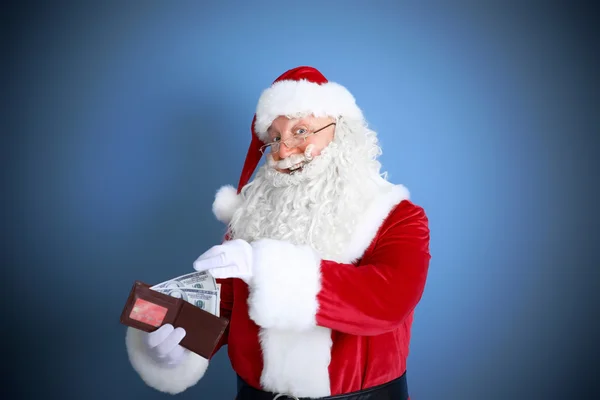 Santa Claus bedrijf portemonnee met geld en creditcard op blauwe achtergrond — Stockfoto