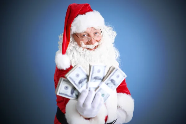 Noel Baba para mavi arka plan üzerinde tutan — Stok fotoğraf