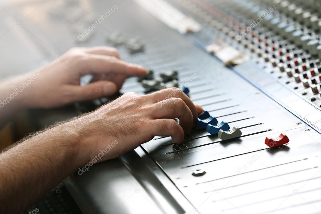 Hands on mixer in a recording studio, close up