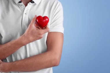 Renk arka plan üzerinde kırmızı kalp tutan genç adam