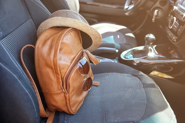 Mochila con sombrero y gafas de sol en el asiento del coche —  Fotos de Stock