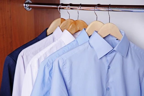 Hangers with male shirts on clothes rail in wardrobe — Stock Photo, Image