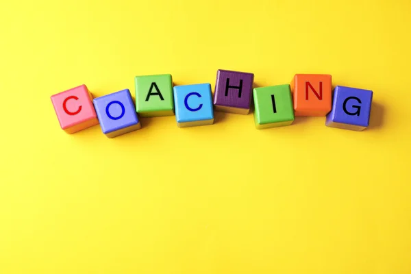 Conceito de coaching. Cubos de madeira sobre fundo amarelo — Fotografia de Stock