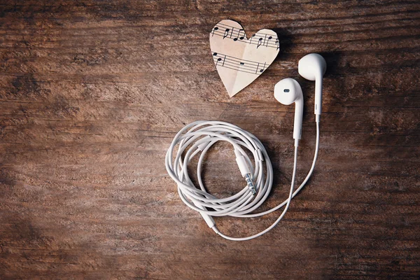 Kağıt kalpler müzik notlar ve ahşap arka plan üzerinde kulaklık — Stok fotoğraf