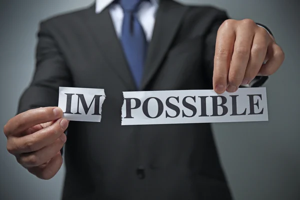 Empresário rasgando papel com palavra impossível — Fotografia de Stock