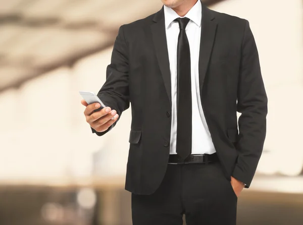 Podnikatel, držení telefonu v ruce na rozmazané pozadí úřadu. Právník a notář koncept. — Stock fotografie