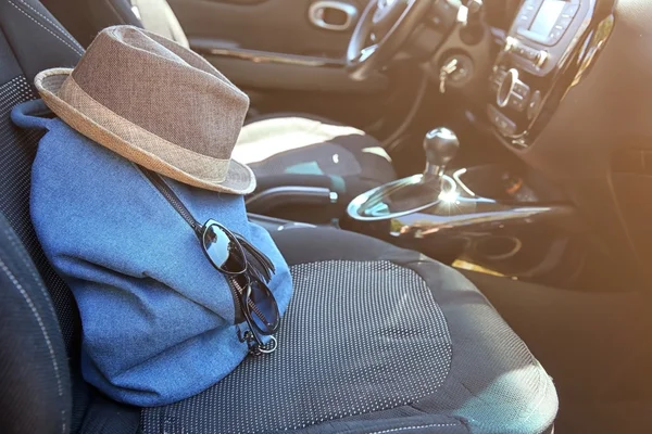 Mochila com chapéu e óculos de sol no assento do carro — Fotografia de Stock