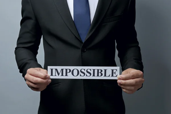 Empresario sosteniendo papel con palabra imposible —  Fotos de Stock