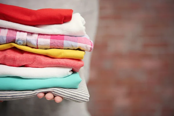 Vrouw met stapel van kleren, close-up — Stockfoto