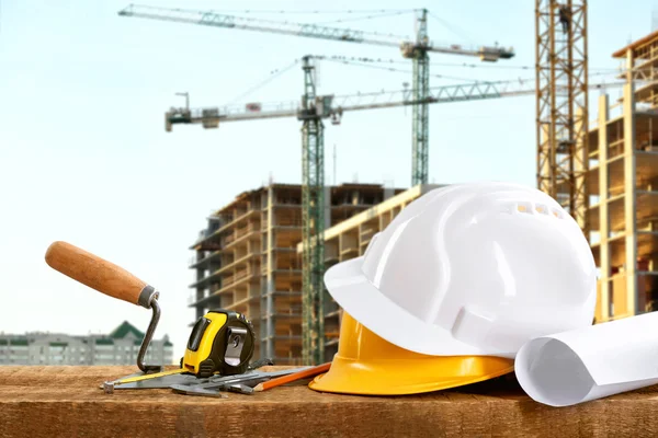 Construction blueprints with tools and helmets on building construction background — Stock Photo, Image