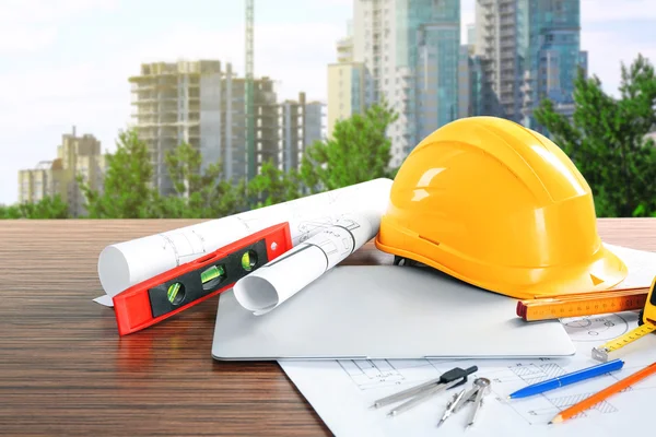 Planos de construcción con herramientas y casco sobre fondo de construcción de edificios —  Fotos de Stock