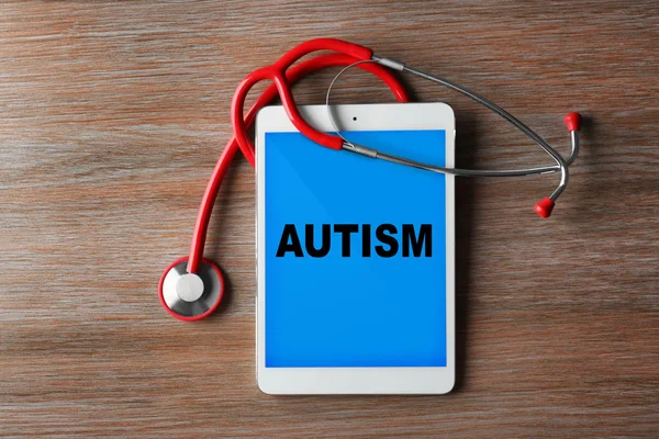 Концепція дитячого аутизму. Червоний стетоскоп і планшет на дерев'яному фоні — стокове фото