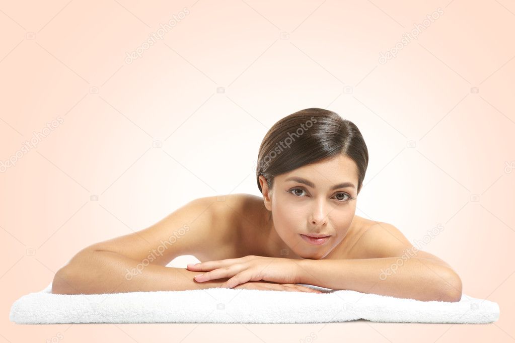 Young beautiful woman with towel on light background